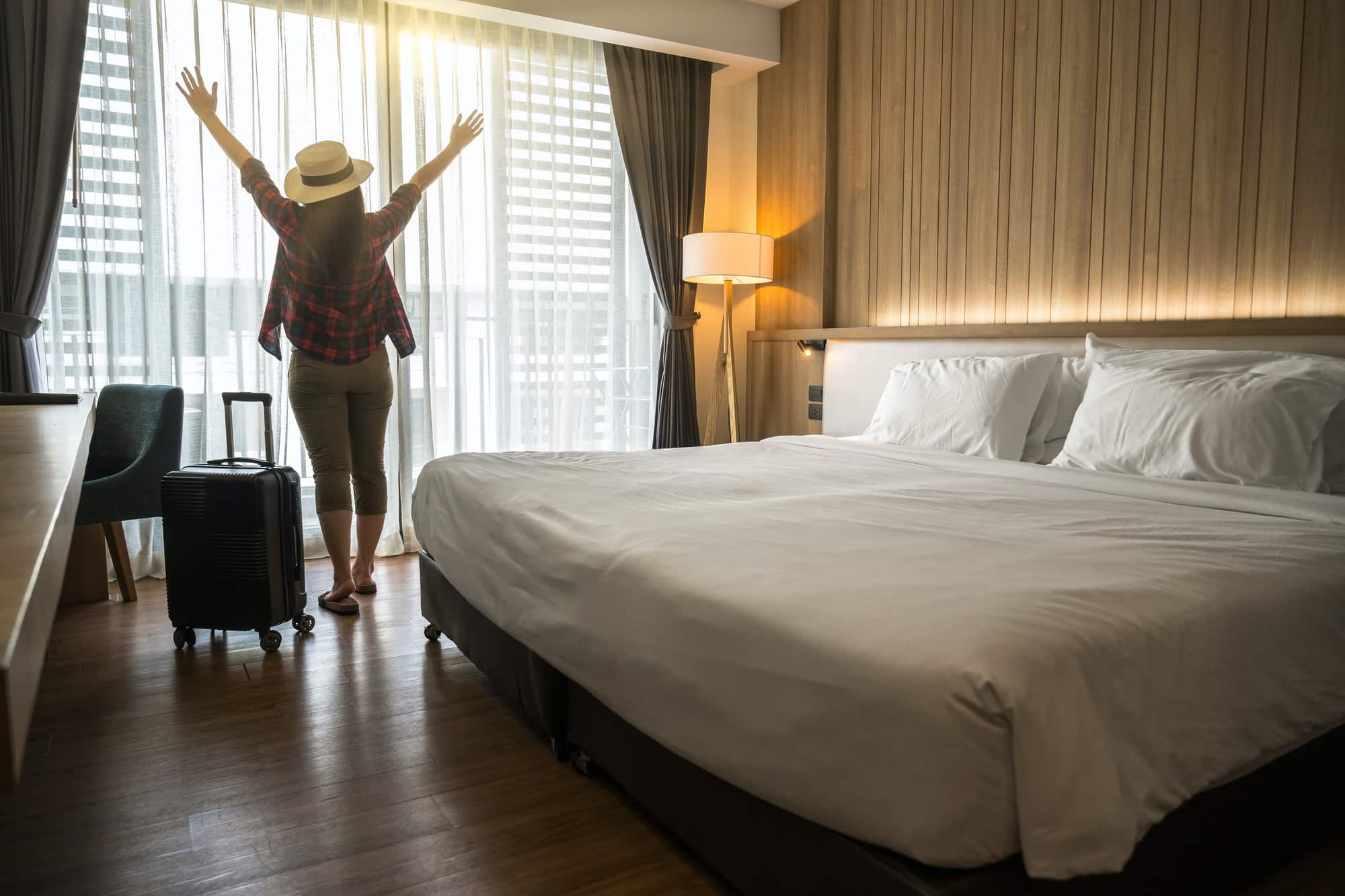 Happiness Asian traveler woman standing with baggage in bedroom of hotel or hostel